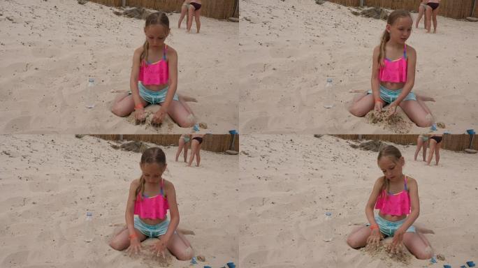 可爱的女孩子玩沙子坐在沙滩上