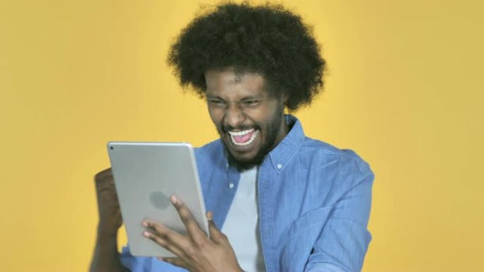 非洲裔美国人在黄色背景上使用平板电脑时对成功感到兴奋