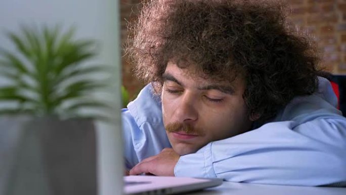 昏昏欲睡的滑稽商人，卷发在工作中打瞌睡，在现代办公室的工作场所睡觉