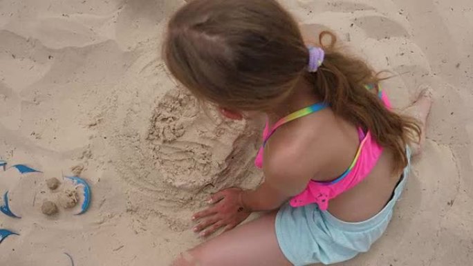 女孩少年在夏日海滩上做沙质蛋糕