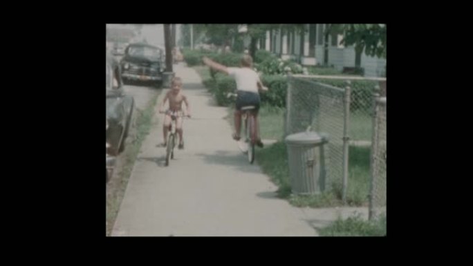 1957男孩骑自行车旁边的老式汽车