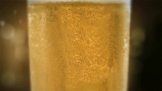 特写慢动作冷光啤酒在酒杯中，酒吧背景上有水滴。精酿啤酒特写