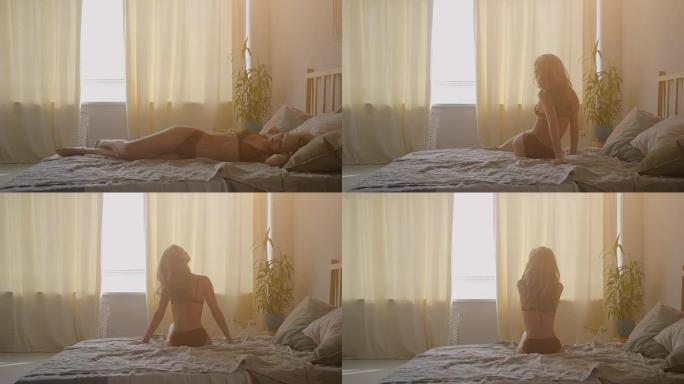 美丽的年轻金发女人在床上享受业余时间。她伸展她性感的身体