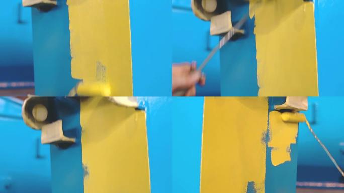 男人正在用手辊将大的蓝色金属细节画成黄色