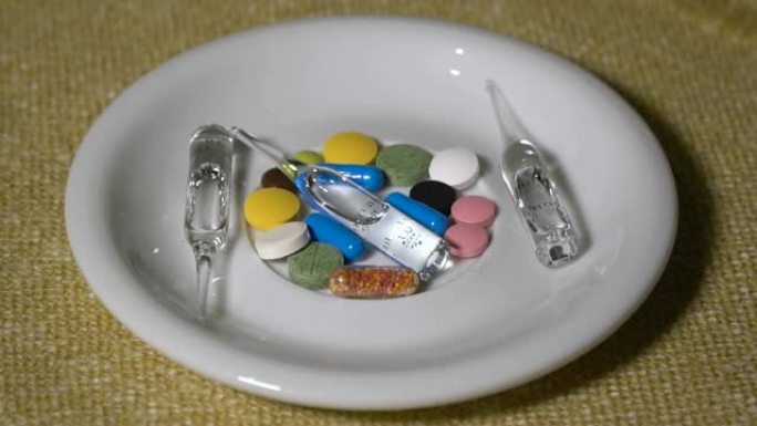 药丸。药物特写。白色盘子上是一堆多色药片和几个安瓿。生物活性添加剂和维生素。特写。慢动作。