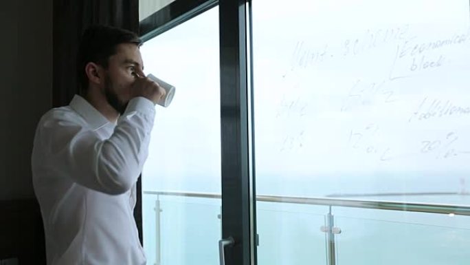 男人喝咖啡，看着写在窗玻璃上的商业计划书