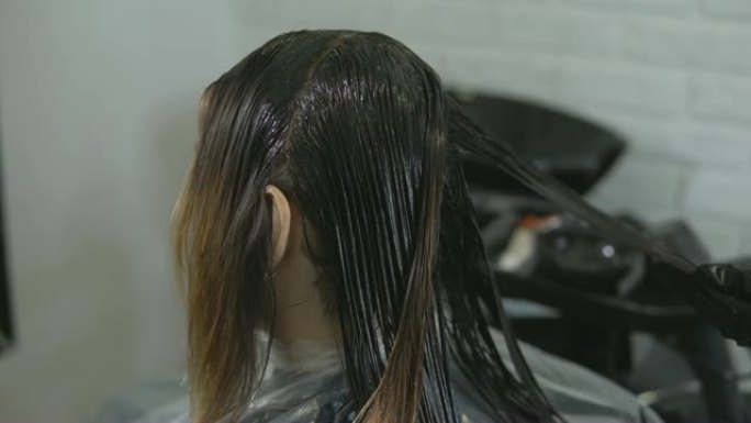 造型师在美容院画一个年轻女人的头发。