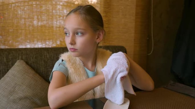 年轻女子女孩坐在咖啡馆的桌子旁，用湿毛巾擦手，准备吃寿司。