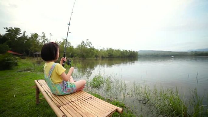 快乐的女孩在湖景钓鱼时拔竿。