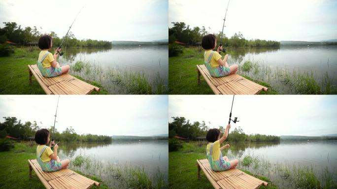 快乐的女孩在湖景钓鱼时拔竿。