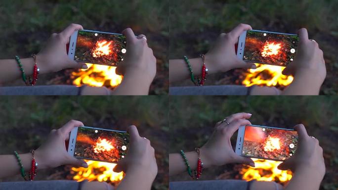 女人用手机拍摄了明亮的篝火 (露营视频)