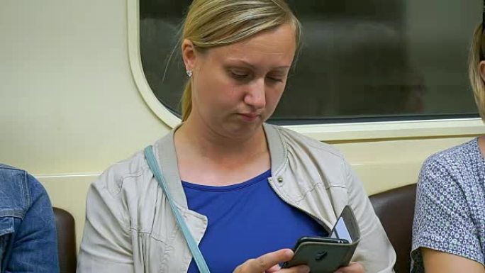 一名中年妇女在地铁里看着智能手机保持清醒。疲倦的女人