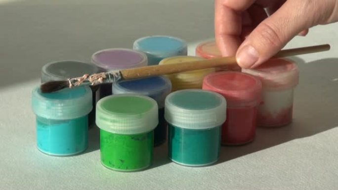 艺术家从一罐丙烯酸水粉颜料中取出刷子