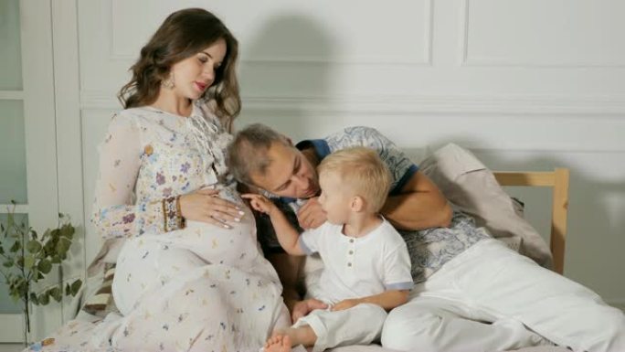 幸福的孕妇与家人在床上