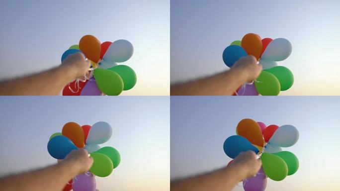 夏天，手拿着一堆彩色气球对着蓝天