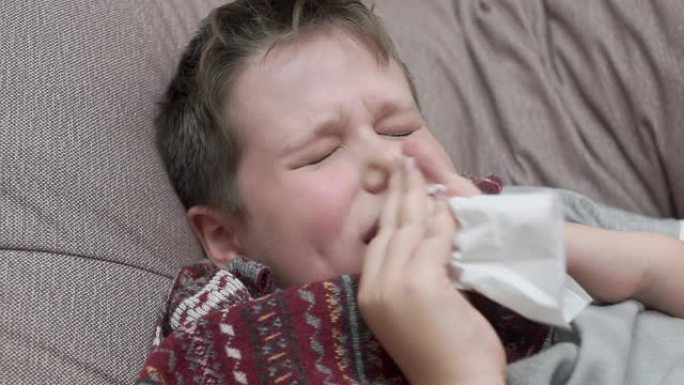 这个男孩用纸巾鼻涕。他感冒了