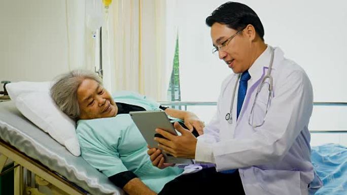 亚洲男性医生使用数字平板电脑与医院病房的高级患者女性讨论
