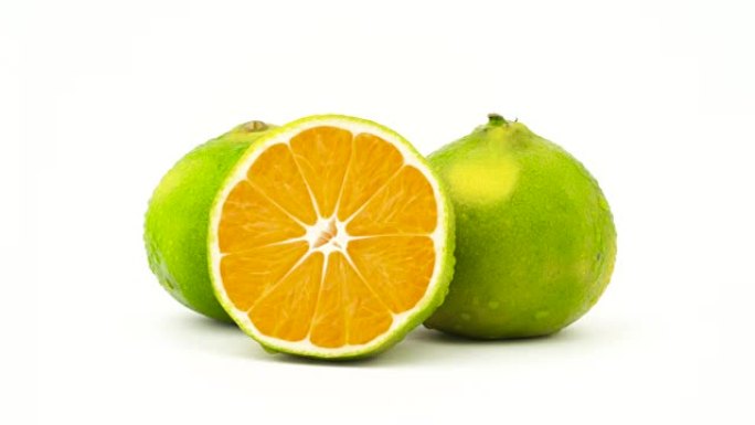 两个完整的半切绿色橘子果实，带有水滴。在转盘上旋转。孤立在白色背景上。特写。宏观。