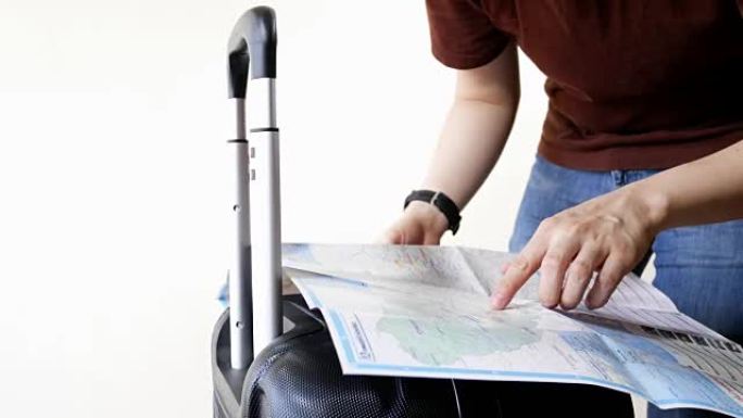 带着旅行行李的男人用纸质地图计划去一个以白色为背景的地方旅行