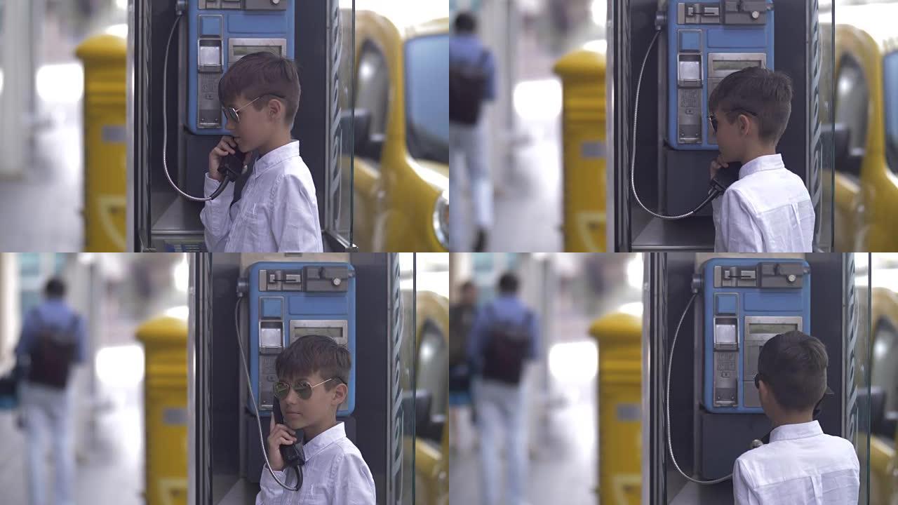 戴着墨镜的有趣男孩正在城市的座机上响起