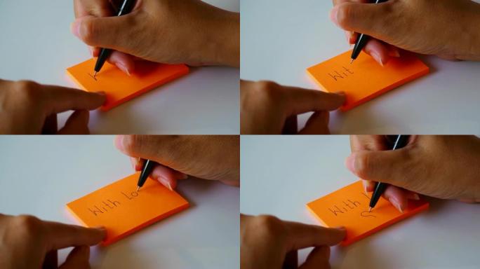 在橙色的便签纸或记事本上手写 “有爱” 一词