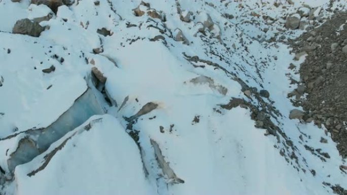 鸟瞰图特写边缘流动的冰川覆盖着高山上的雪和石头。冰川融化的自然破坏和全球变暖