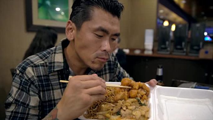 慢动作纹身亚洲男子吃和吞食中国外卖食品
