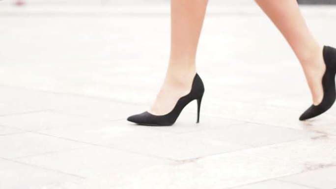 穿着黑色高跟鞋的性感女人腿走在城市街道上。Steadicam稳定射击，女性腿穿着高跟鞋，特写。电影镜