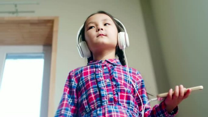 漂亮的亚洲小女孩在家里听音乐和跳舞