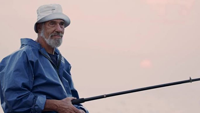 老渔夫站在海边岩石上，在夕阳下钓鱼