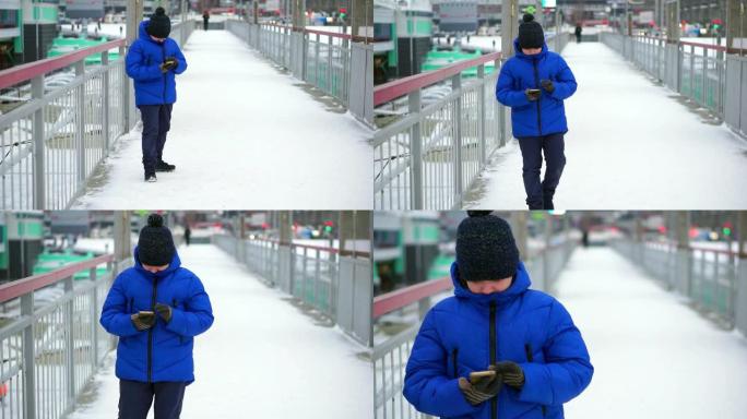 身穿蓝色羽绒服的男孩少年在街上阅读智能手机信息。