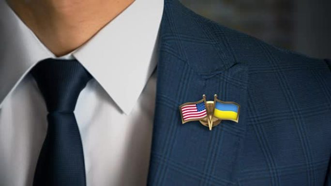 商人走向相机，带着朋友国家的旗帜别针美利坚合众国-乌克兰