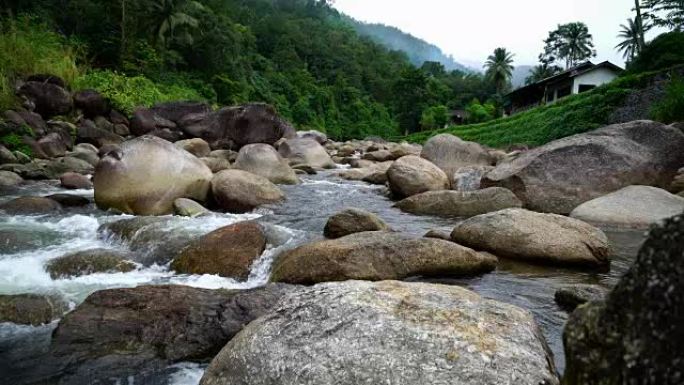 自然水流从山上经过许多岩石到乡村小村庄的河流。瀑布声降下来放松平静与和平。