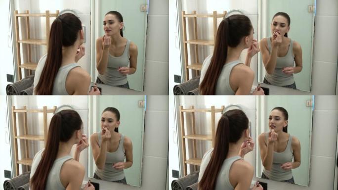 化妆。女人在浴室的嘴唇上涂上液体唇膏