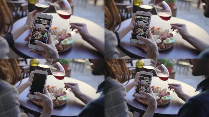 特写女人在餐馆里拍摄食物和葡萄酒的照片。