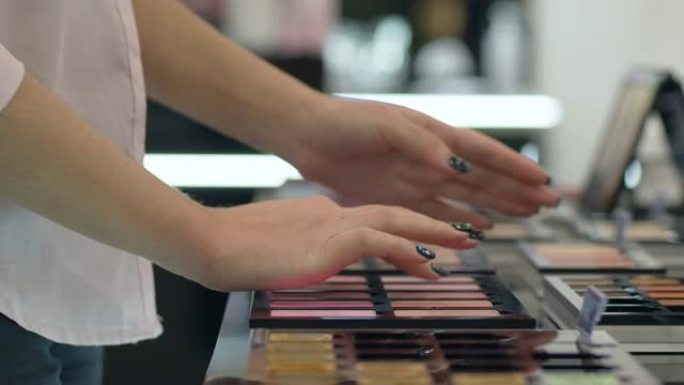 时尚购物女孩选择新的胭脂色调用于粉底化妆，并在化妆品店进行测试