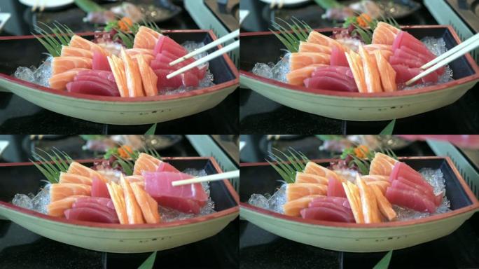 手持筷子拿新鲜金枪鱼生鱼片的前视图