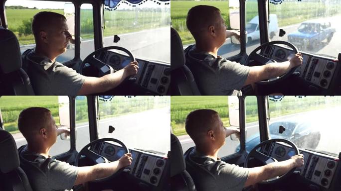 在炎热的夏日，一名男子握着方向盘，驾驶卡车穿过乡村。卡车司机简介。卡车司机在车里。侧视图关闭慢动作