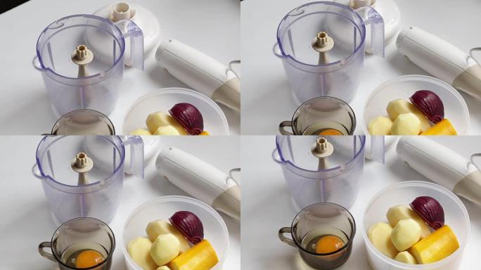 桌子上是一个用来研磨蔬菜的搅拌机。容器旁边是土豆，西葫芦和洋葱。玻璃杯里有一个鸡蛋。