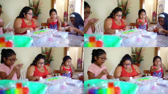 快乐的墨西哥裔美国家庭一起做手工，做精美的珠饰。视频片段与全景摄像机运动
