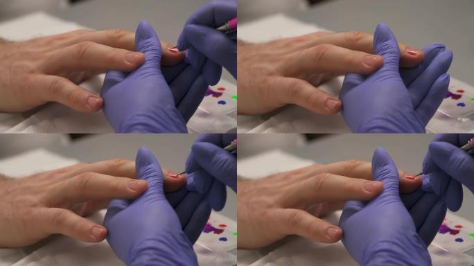 专业美甲师在美容院将红色指甲油涂在男士指甲上。