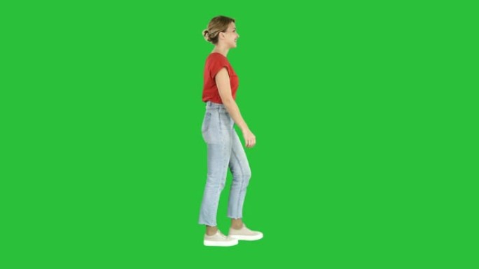 穿着红色t恤、牛仔裤和运动鞋的女人走在绿色屏幕上，色键