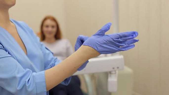 女牙医的手在办公室戴上蓝色消毒手套的特写镜头。
