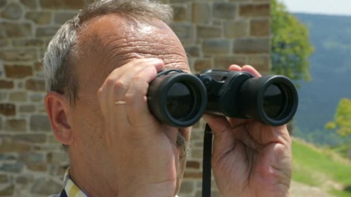 男性游客通过双筒望远镜观看