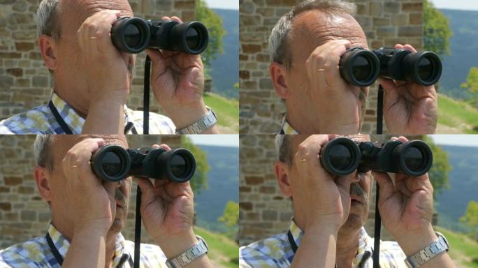 男性游客通过双筒望远镜观看