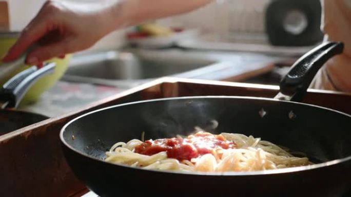 在煎锅中煮在意大利面条上加入番茄酱，特写镜头