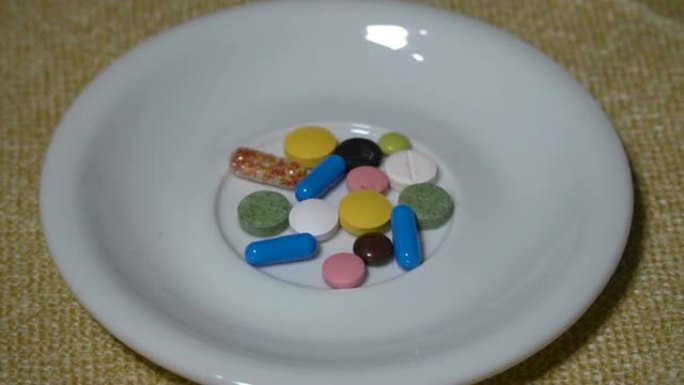 药丸。药物特写。一堆多色药片躺在一个白色的碟子上。生物活性添加剂和维生素。特写。慢动作。