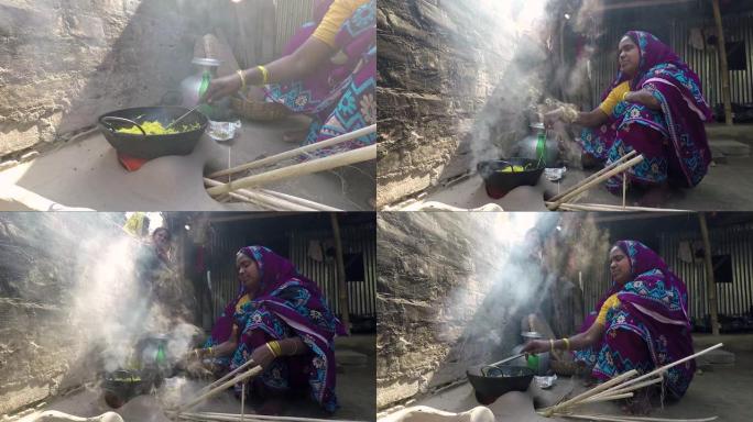女人在传统的粘土炉上做饭，跟踪从火和炒锅中射出的东西。