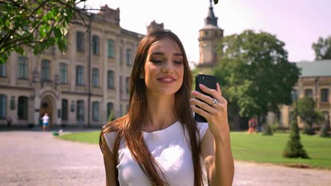 漂亮的年轻女子白天站在公园里，用视频聊天，交流的概念