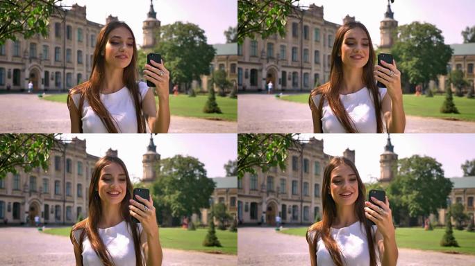 漂亮的年轻女子白天站在公园里，用视频聊天，交流的概念